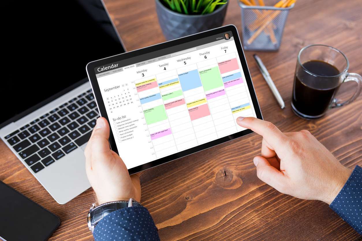 Man using calendar app on tablet at work Man using calendar app on tablet in office
